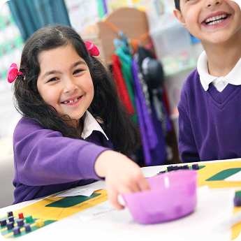Young pupils in Little Rainbow Nursery laughing together during a craft activity