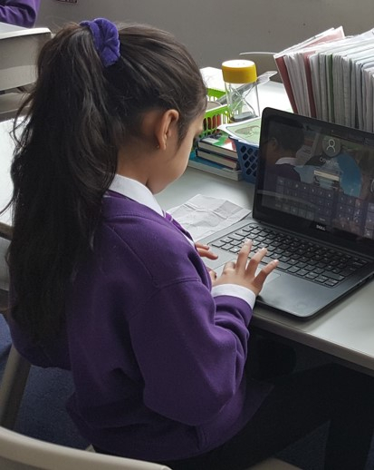 A pupil watching a video on a laptop at her desk