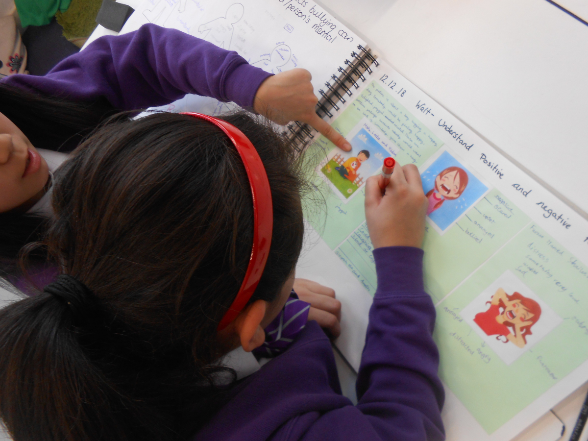 Pupils pointing at pictures in a PSHE workbook