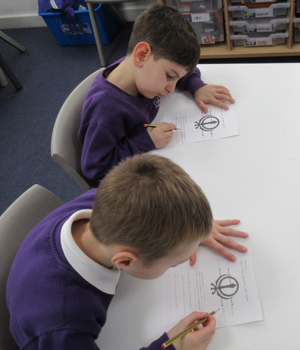 Two pupils drawing the Sikh Khanda symbol in an RE lesson