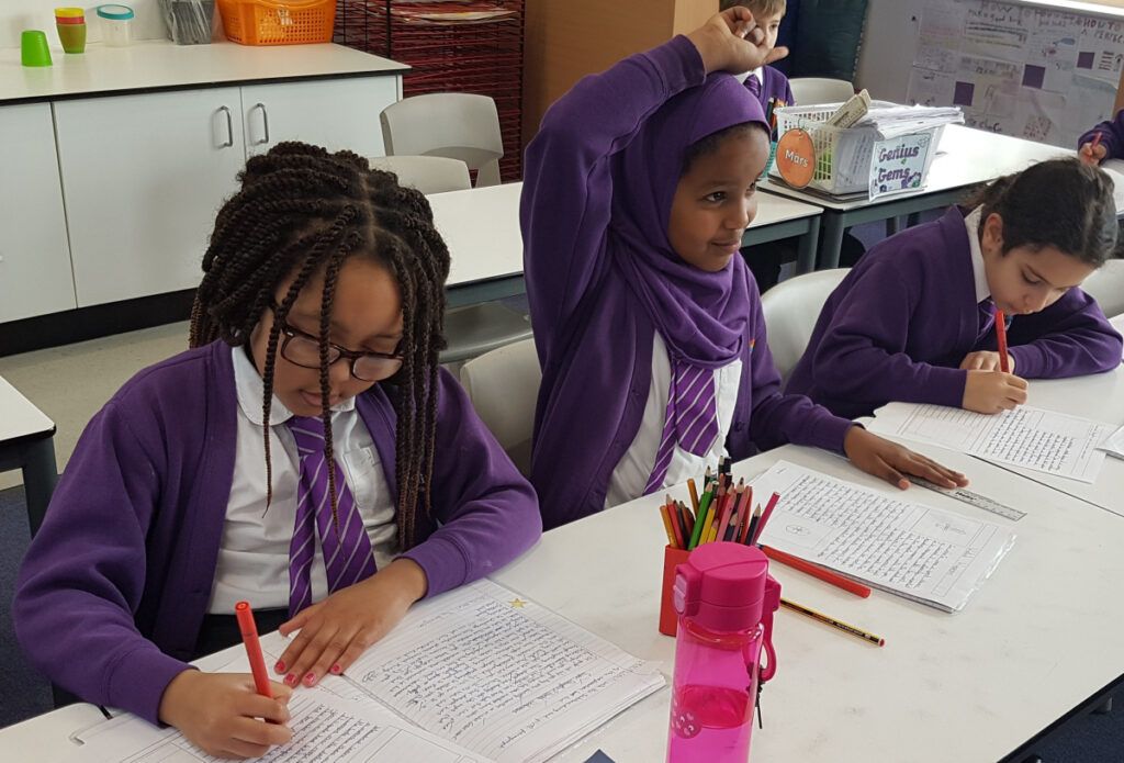Three pupils working on a piece of writing in class