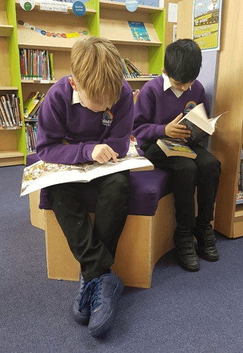 Two pupils reading books in the school library